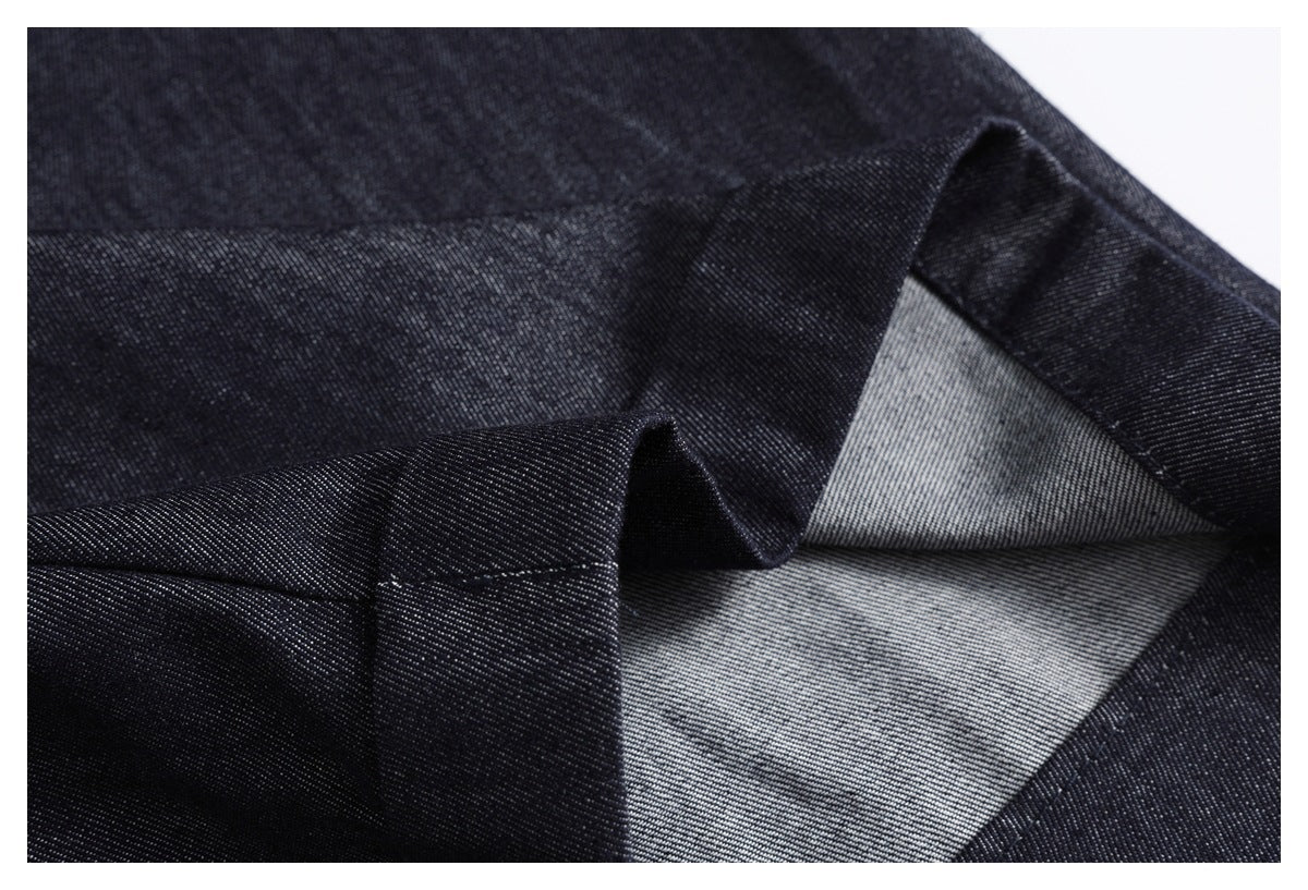 Close-up of dark indigo fabric folded to show the lighter reverse side and stitched edge.