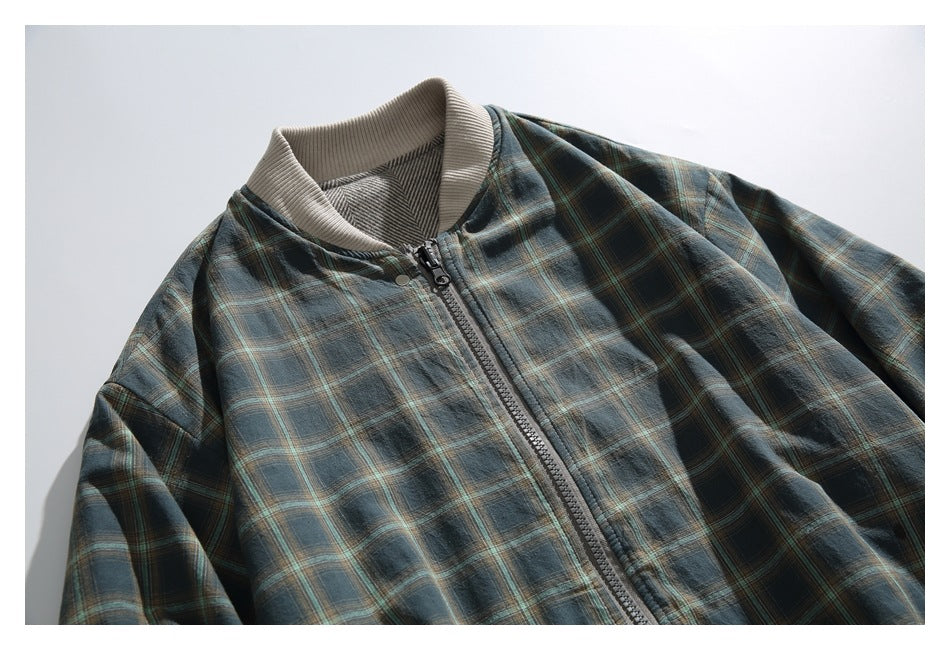 Close view of a dark plaid jacket front with a full-length zipper and cream ribbed collar.