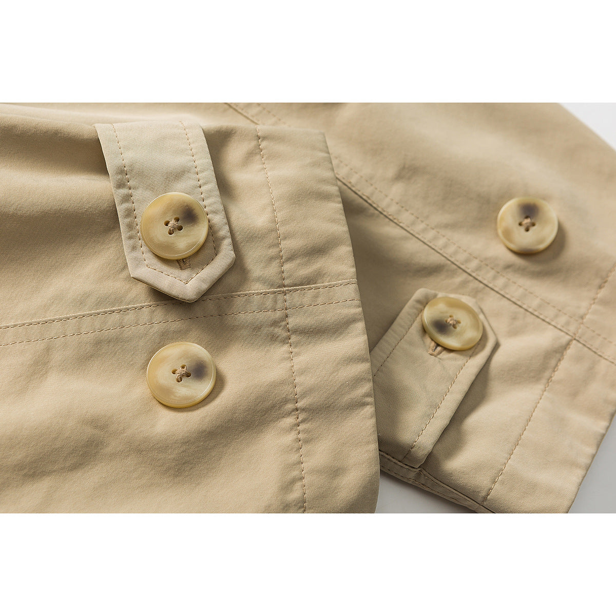 Close-up of tan coat fabric, stitched button tabs, and several round buttons.