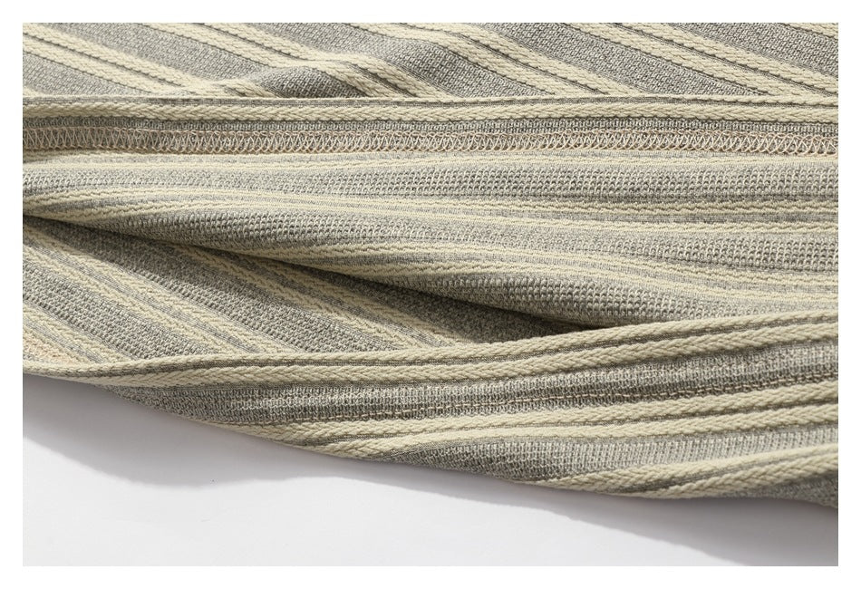 Close-up of the striped knit garment's folded edge and overlocked seam.