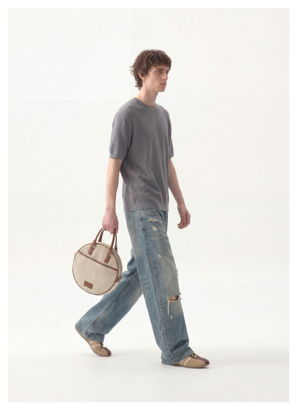 Model walking in a gray textured short-sleeve crewneck top and distressed blue jeans.