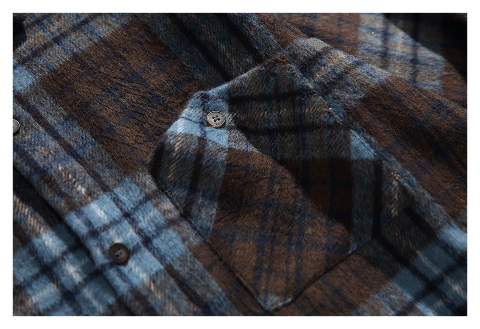 Close-up of a buttoned chest pocket on the brown and blue plaid shirt.