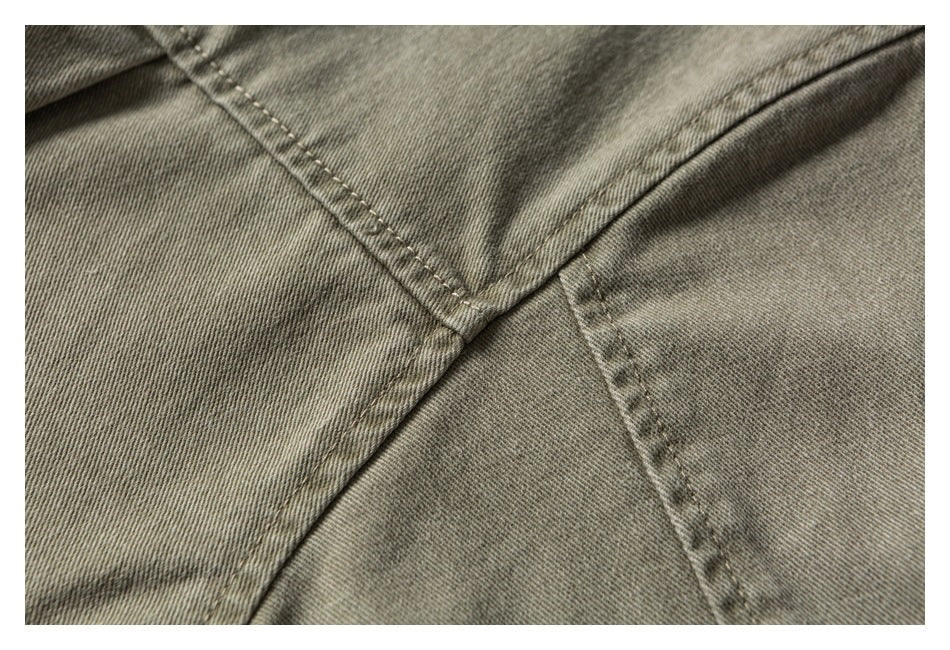 Close-up of olive-gray garment fabric with intersecting stitched seams.