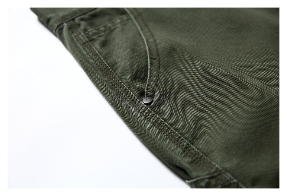 Close-up of an olive green trouser pocket with curved stitching and a metal rivet.