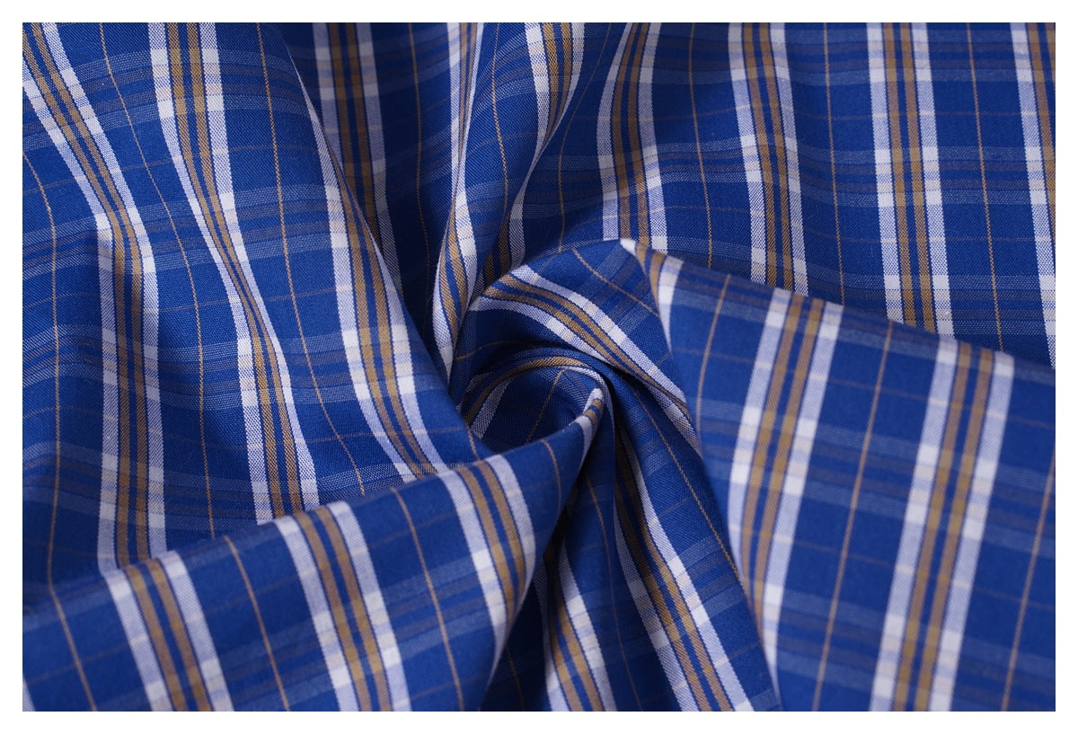 Close-up of blue plaid fabric with white and tan stripes, gathered into folds.