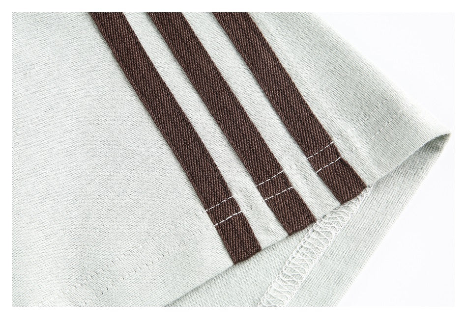 Close-up of a pale gray garment hem with three dark brown stripes and visible stitching.