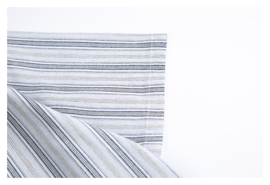 Close-up of white fabric with fine blue and gray horizontal stripes, folded to show the pattern in two directions.