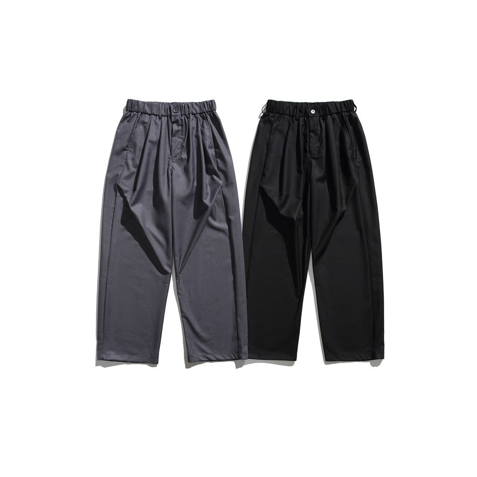 Front view of relaxed trousers in charcoal gray and black, with elastic waistbands and tapered legs.