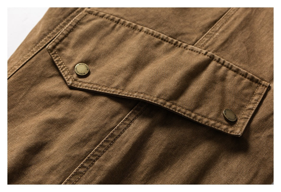 Close-up of a brown garment pocket flap with contrast stitching and two metal buttons.