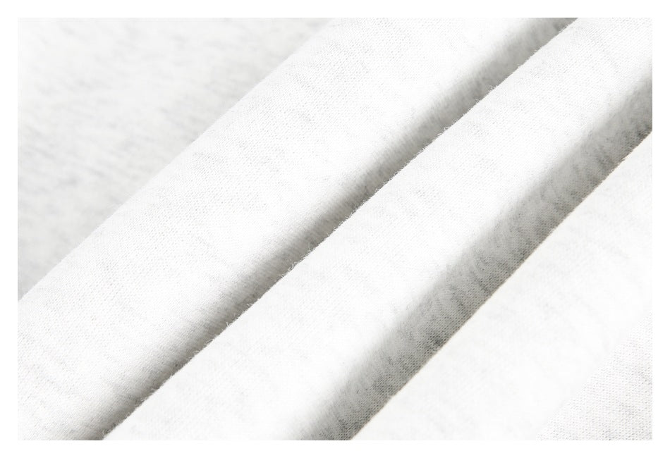 Close-up of smooth off-white garment fabric arranged in soft folds.