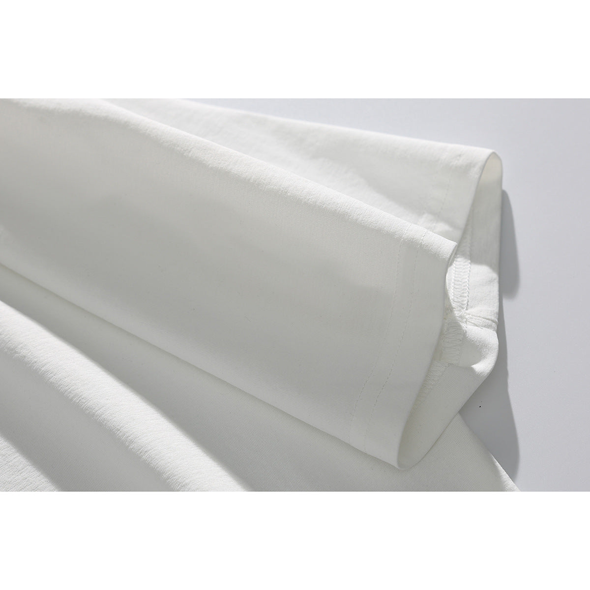 Close-up of the sleeve hem and stitching on a plain white T-shirt.