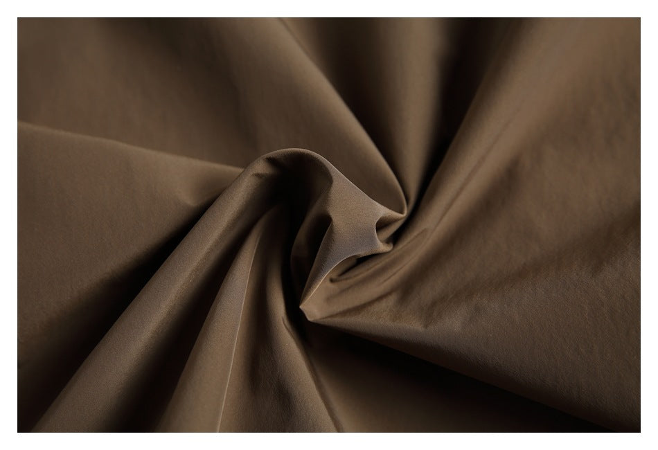 Close-up of brown fabric gathered into soft folds, showing its surface and drape.