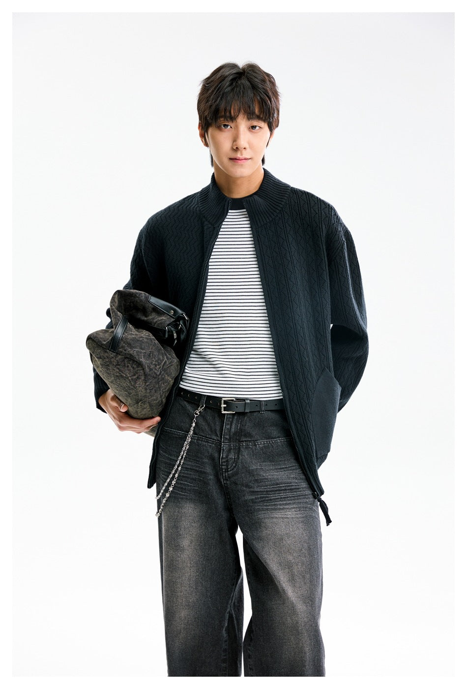 Model wearing an open dark patterned knit cardigan over a striped shirt, shown from the front.