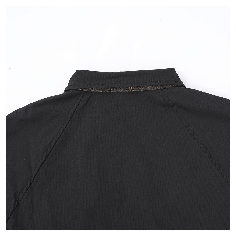 Close view of the back upper section of a black jacket, with a collar and raglan seams.