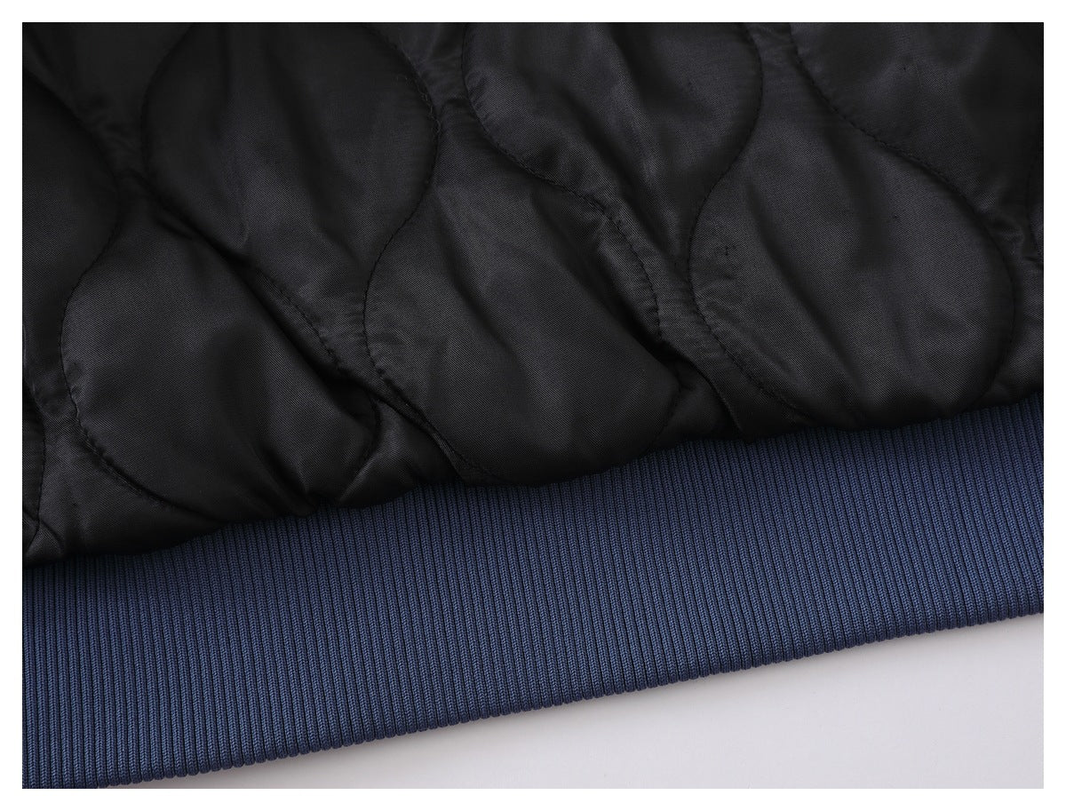 Close-up of black quilted garment fabric beside a dark blue ribbed hem.