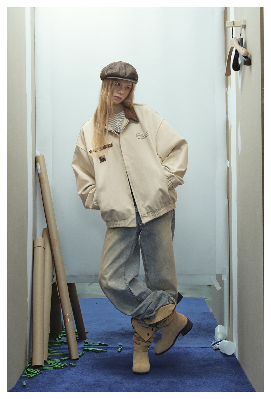 Model wearing a light khaki zip jacket with brown collar, striped top, faded jeans and tan boots