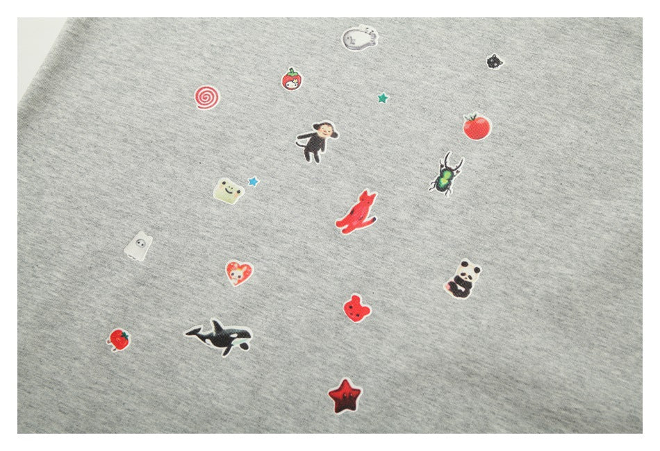 Scattered small colorful character, animal, food, and star motifs on heather-gray shirt fabric.