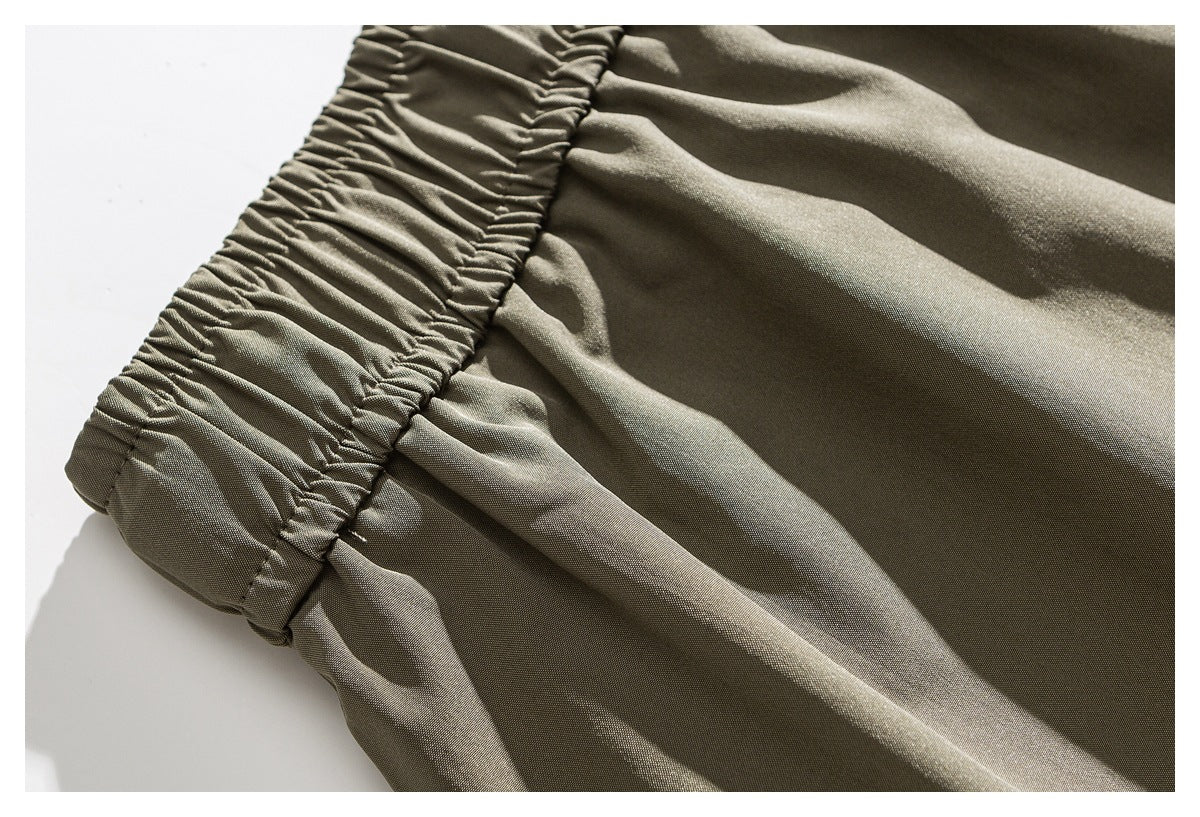 Close-up of khaki trousers showing a gathered elastic edge and stitched fabric panels.