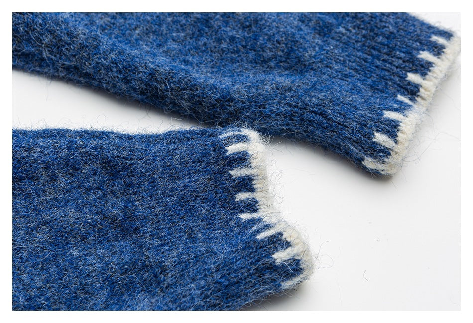 Close-up of blue knit sweater cuffs with white patterned edging.