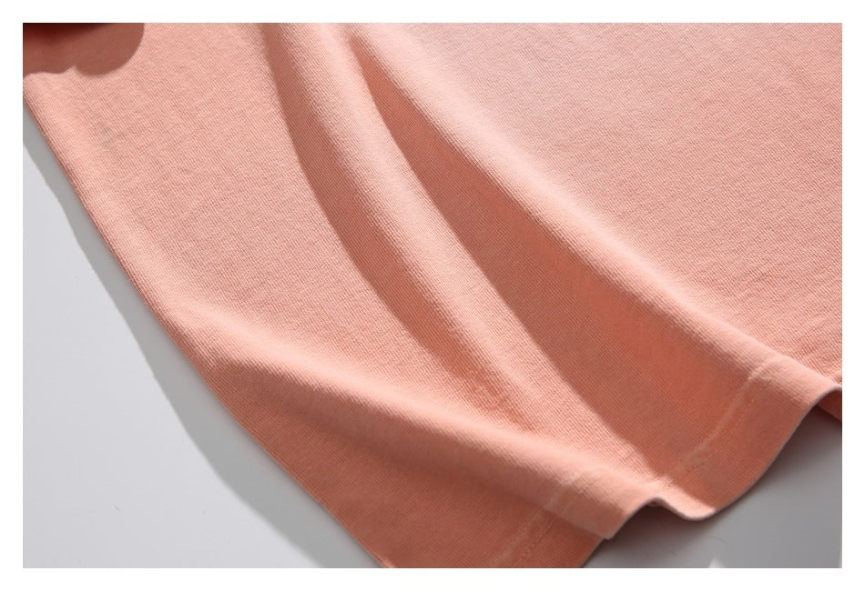 Close-up of the peach T-shirt fabric and stitched bottom hem.