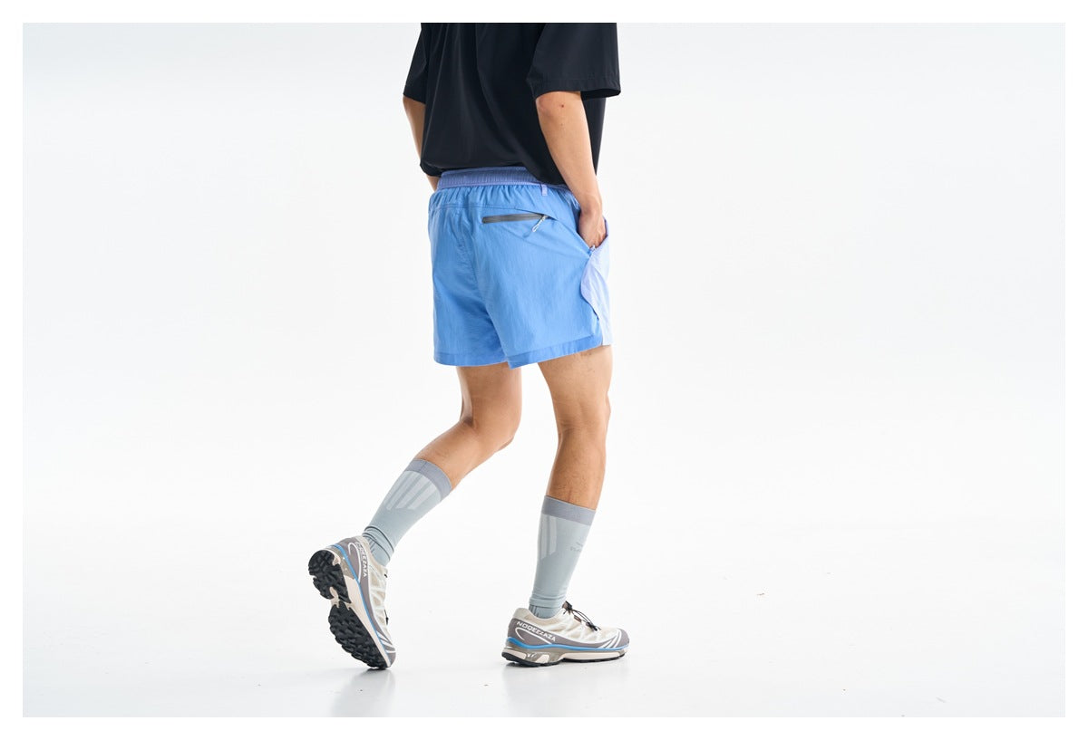Rear view of light blue shorts worn by a model, showing an elastic waistband and a zippered back pocket.