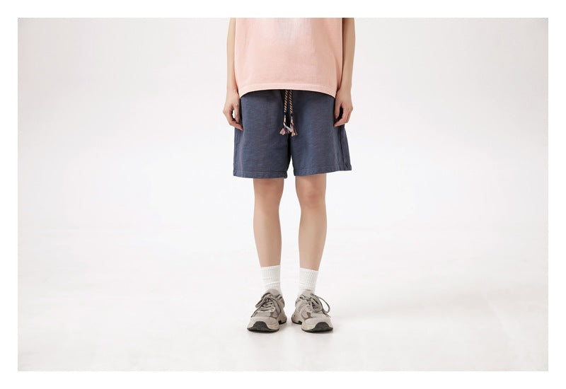 Front view of a model wearing navy blue shorts with tasseled drawstrings.
