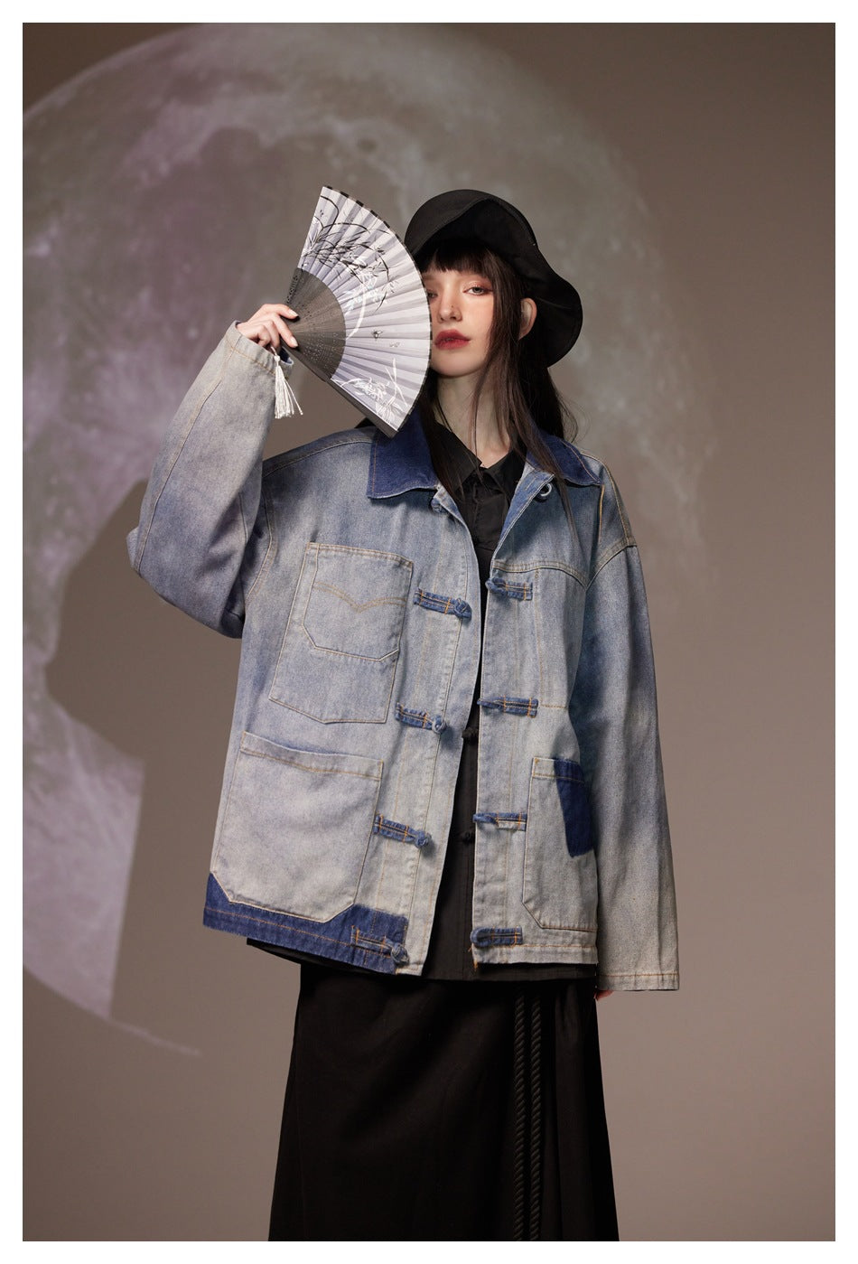 Model wearing a gray denim jacket with a dark blue collar and contrast pockets, holding an open folding fan.
