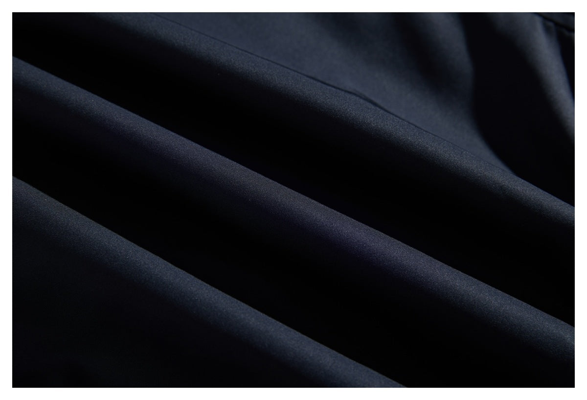 Close-up of smooth dark navy fabric arranged in broad folds.