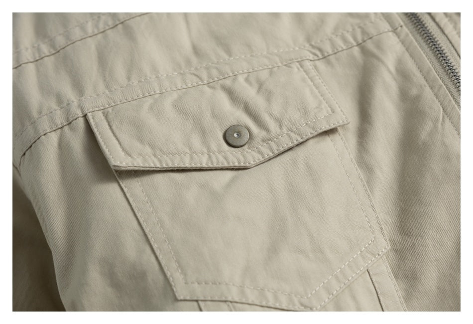 Close-up of a beige garment flap pocket with a metal snap and a zipper along the edge.