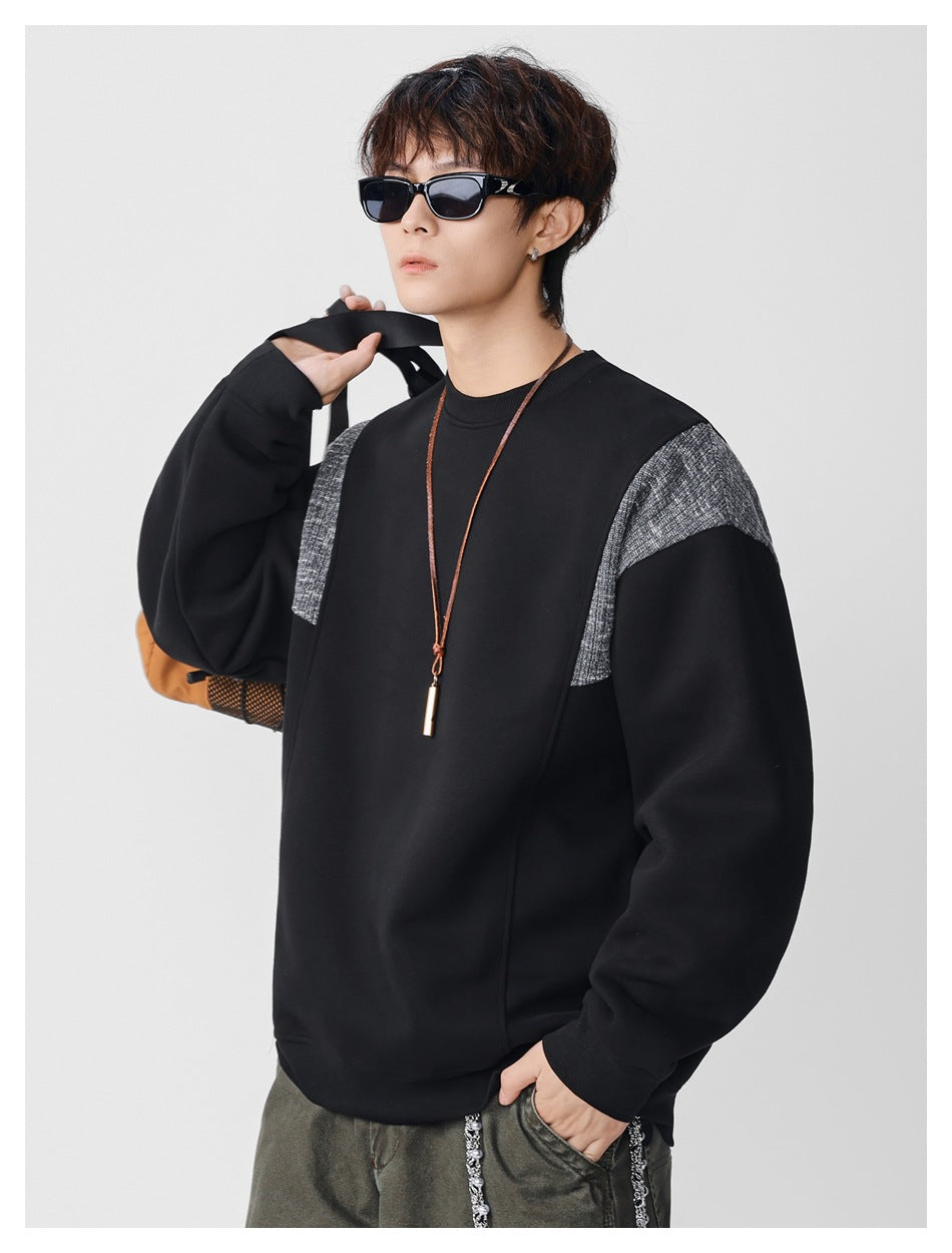 Model wearing a black crewneck sweatshirt with gray textured shoulder panels and ribbed cuffs.
