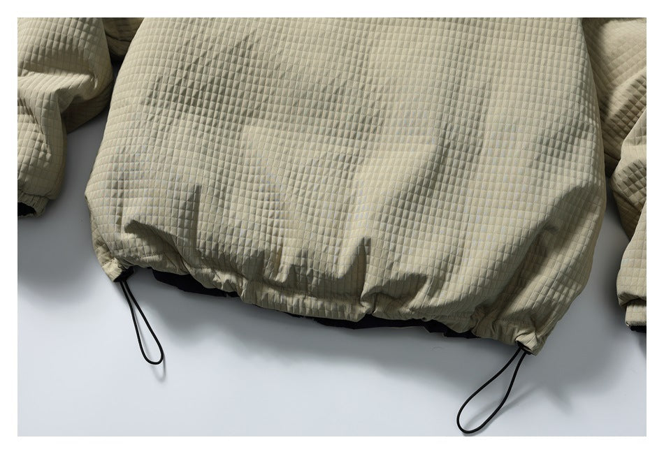 Close-up of the beige quilted jacket's gathered hem and black drawcord loops.