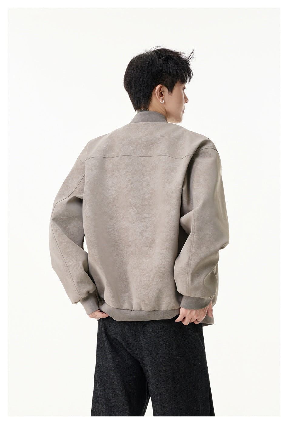 Rear view of a model wearing a taupe bomber jacket with a ribbed collar, cuffs, and hem.