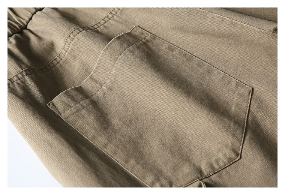 Close-up of a large patch pocket and stitching on khaki trousers.