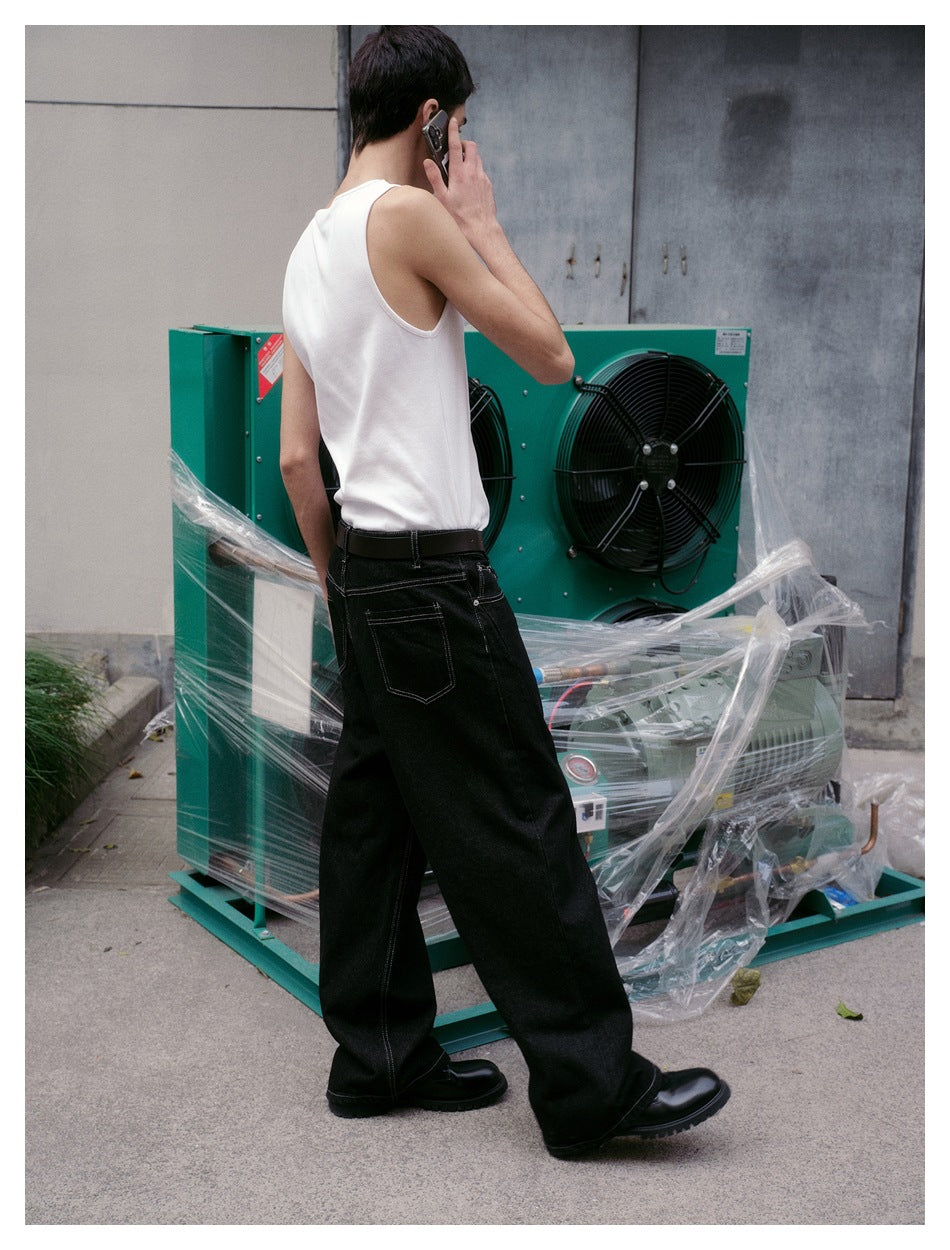 Three-quarter rear view of a model wearing a white tank top and black wide-leg jeans with back pockets.