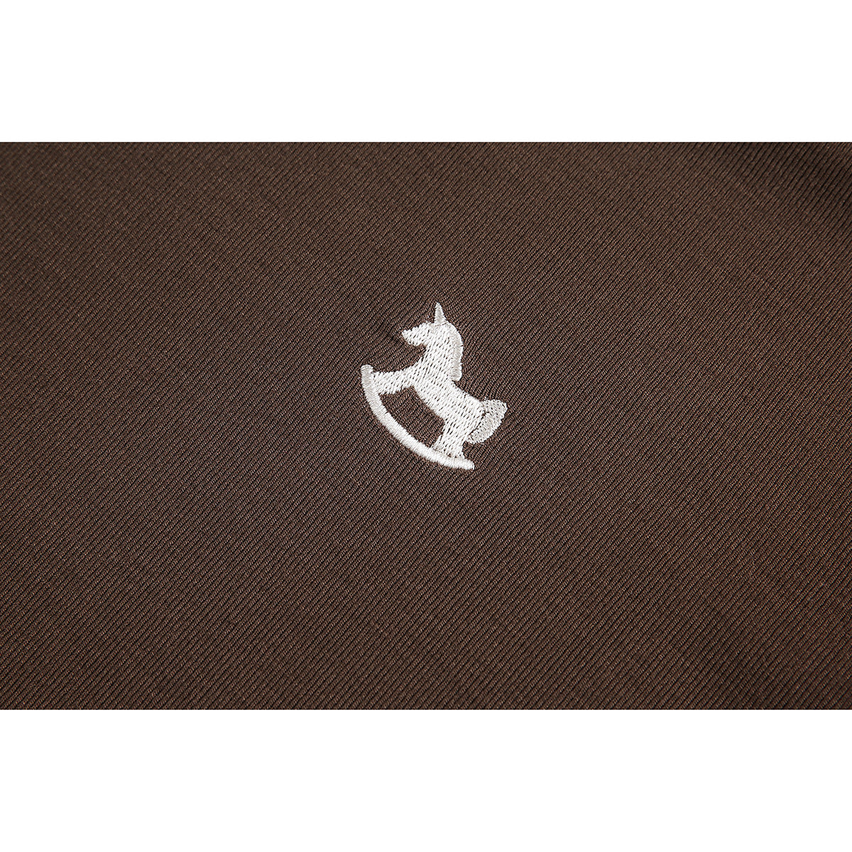 White rocking-horse embroidery on brown fabric.