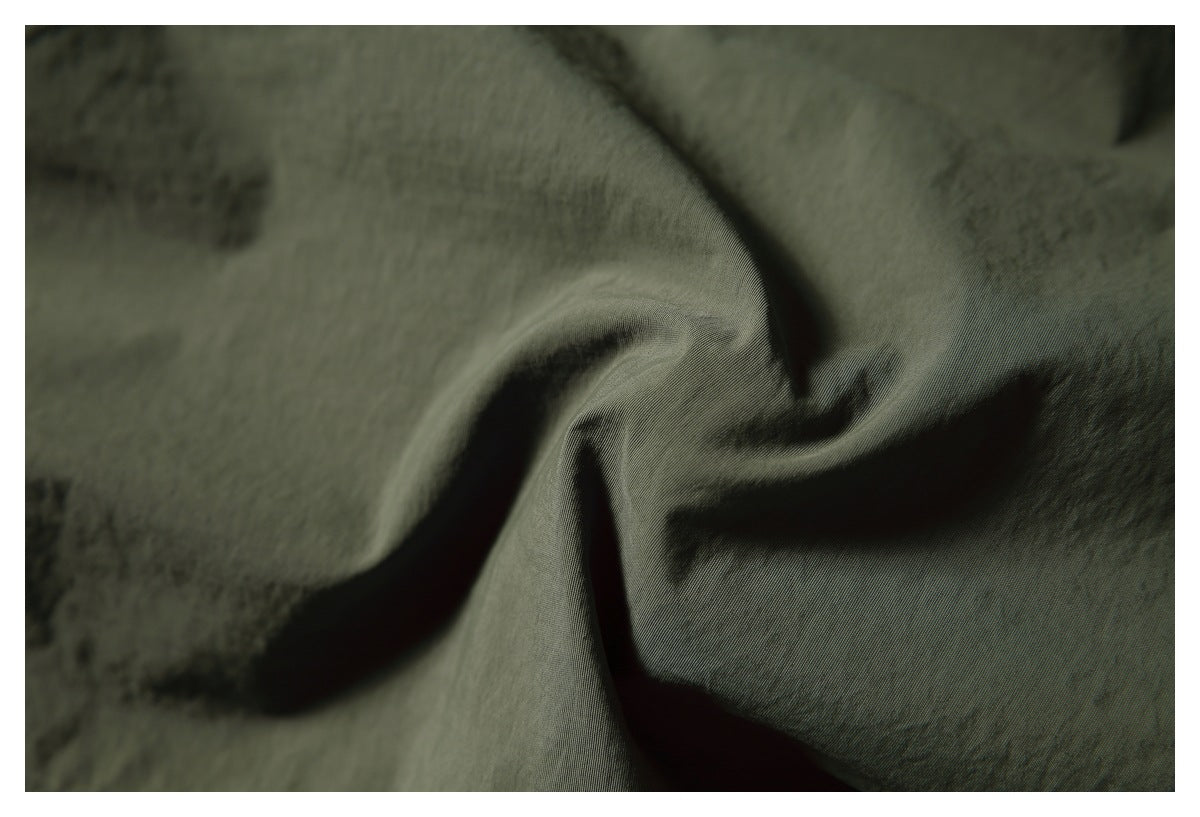 Macro view of dark olive fabric gathered into soft folds.