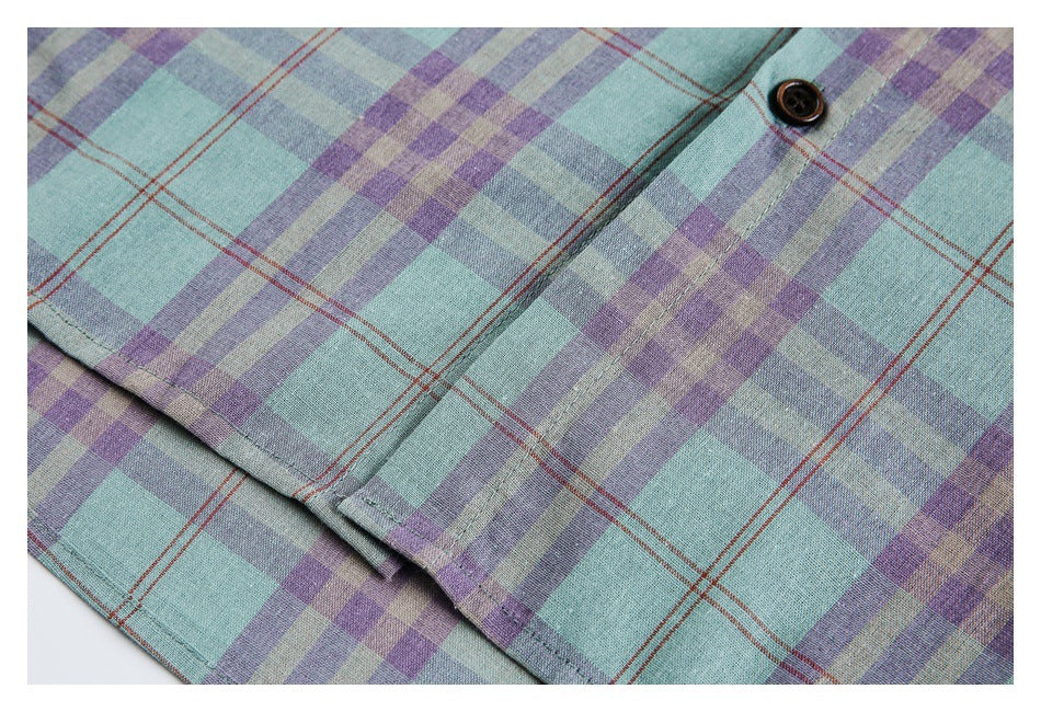 Close-up of the button placket and a dark button on a mint, lavender, and gray plaid shirt.