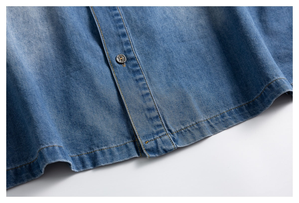Close-up of a blue denim shirt lower front, showing the button placket and stitched hem.