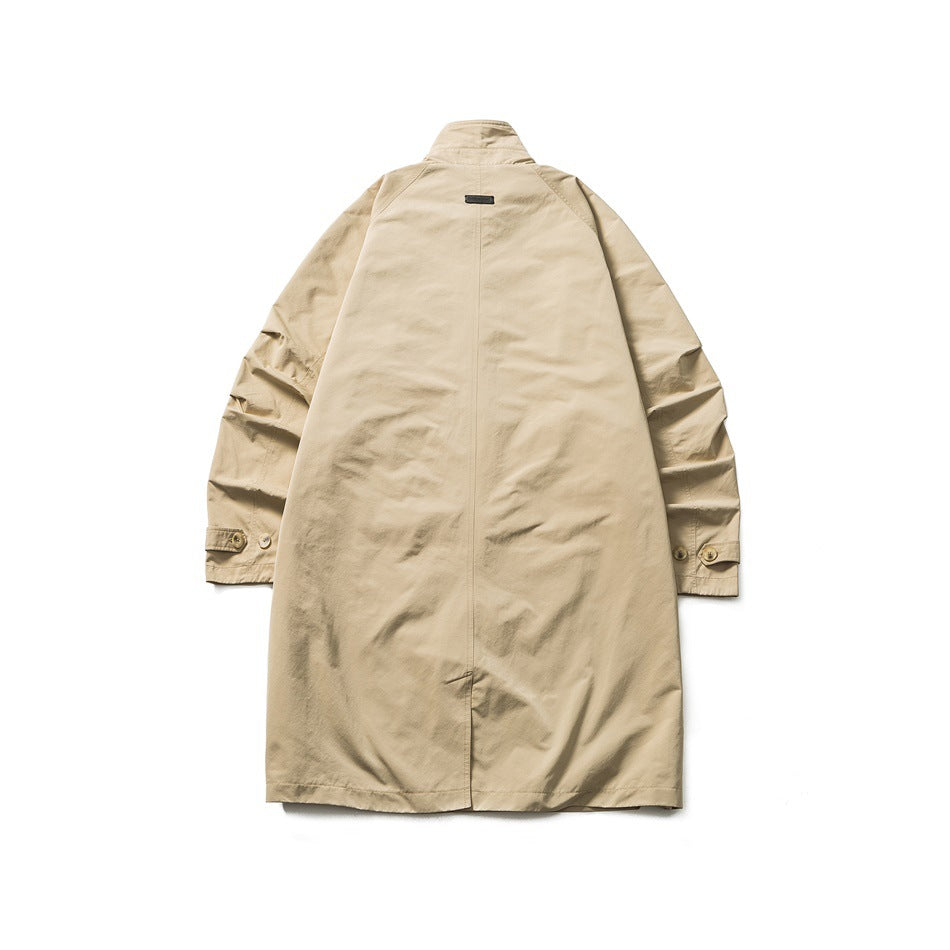 Back view of khaki mid-length coat laid flat showing center seam, small upper back label, raglan sleeves and hem vent