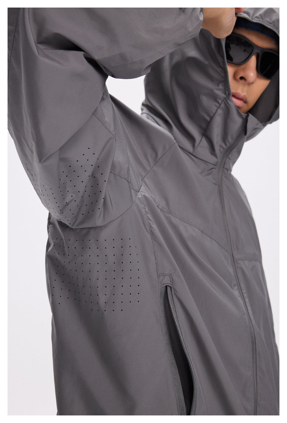 Close-up of a charcoal gray hooded jacket showing perforated underarm and side panels and a zippered pocket.
