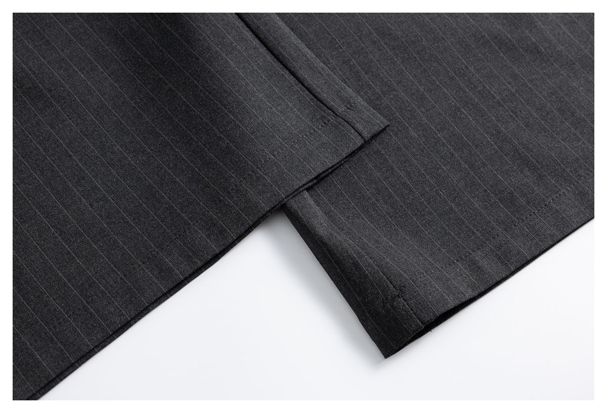 Close-up of the overlapping hems of charcoal pinstripe trousers.