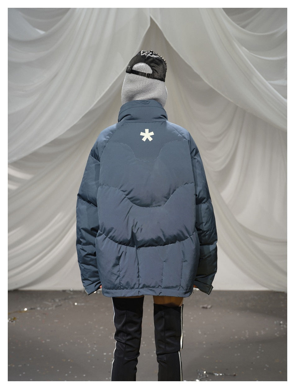 Closer back view of a model wearing a blue-gray quilted puffer jacket with a white star-shaped mark.