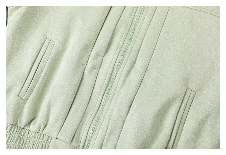 Close-up of the pale mint jacket's front zipper, vertical seam details, welt pockets, and gathered hem.