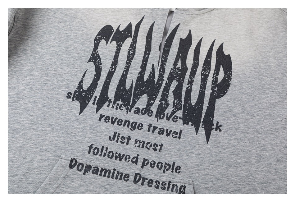 Close-up of distressed black English lettering printed on the front of a light gray pullover.