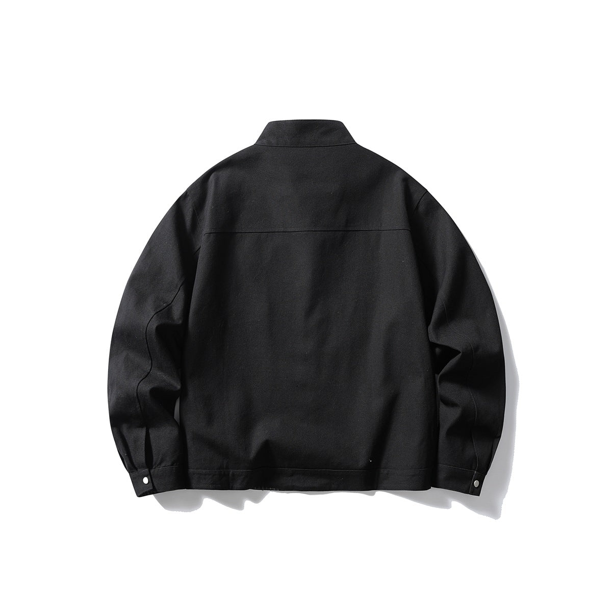 Back view of a black stand-collar jacket with long sleeves, a horizontal shoulder seam, and snap cuffs.