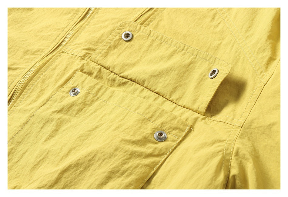Close-up of a mustard-yellow jacket front with a zipper and snap-fastened flap pockets.