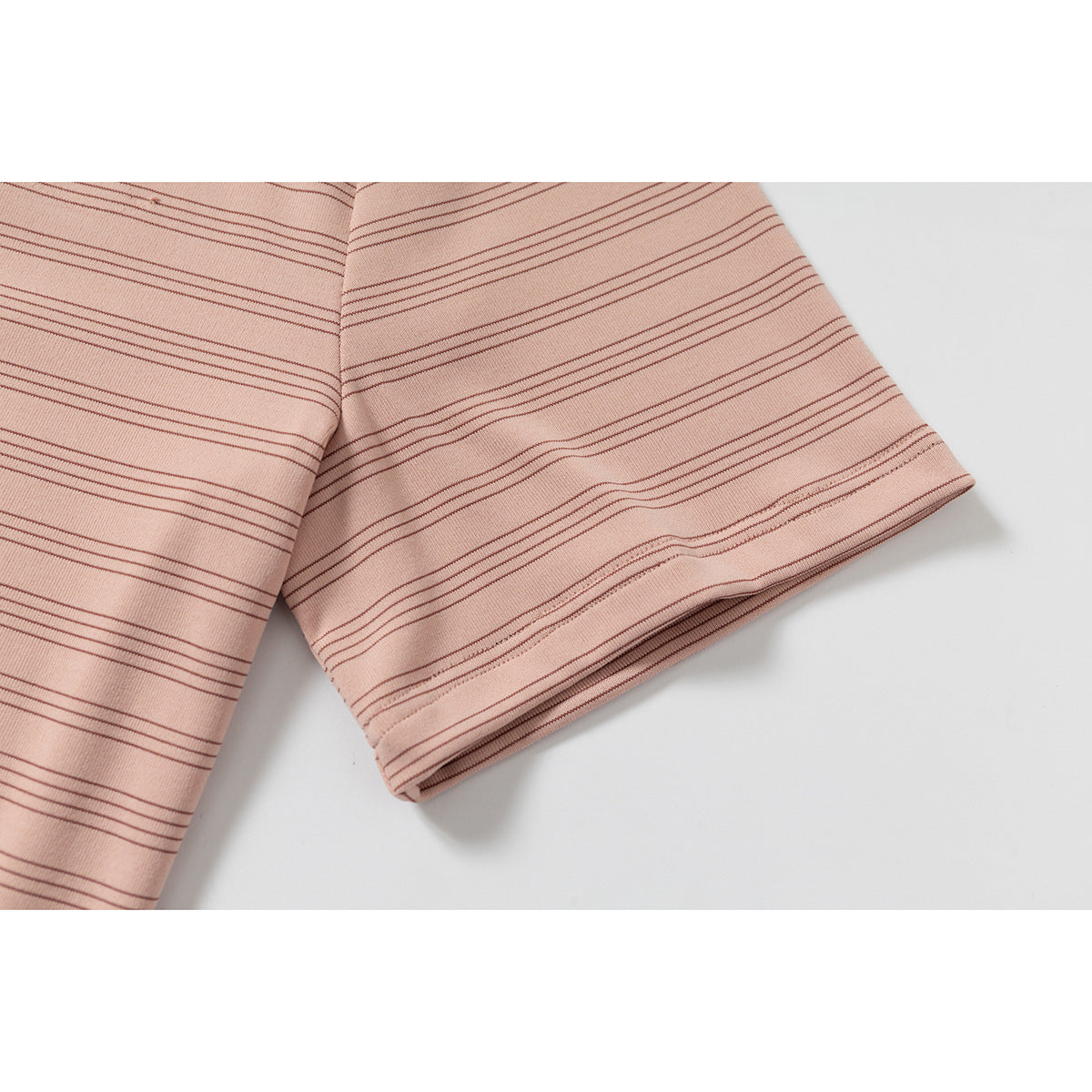 Close-up of the short sleeve and hem of a peach-pink shirt with fine dark horizontal stripes.