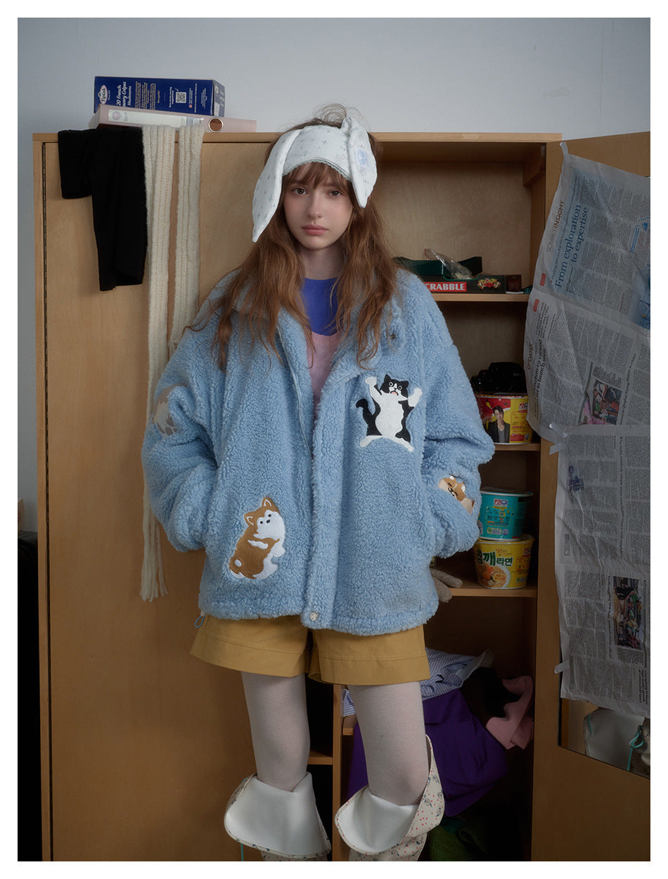 Front view of a model wearing a light-blue plush jacket decorated with animal appliqués and mustard shorts.