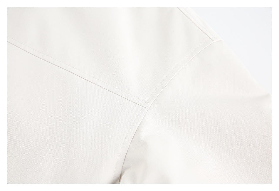 Close-up of ivory jacket fabric with curved panel seams and topstitching.