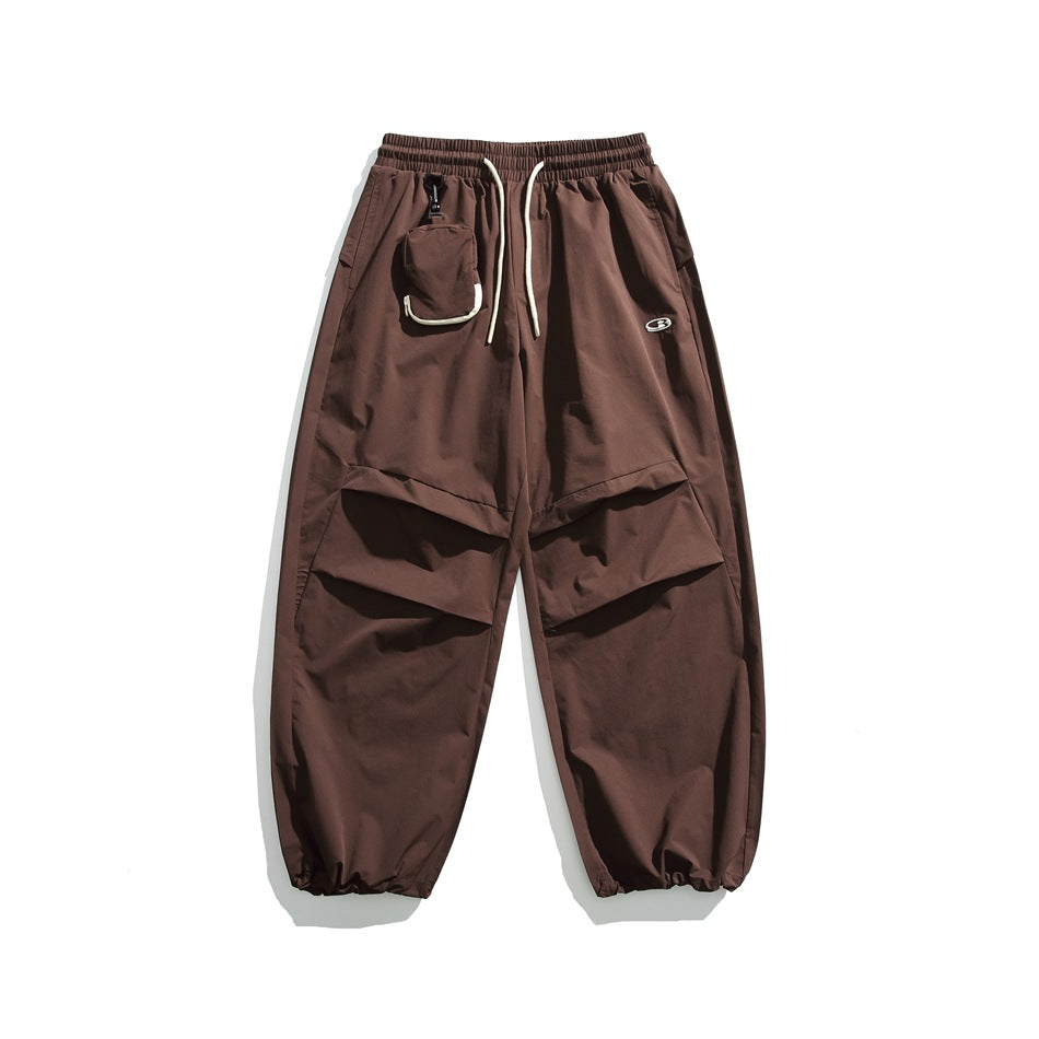 Coffee brown wide-leg pants with cream drawstring, clipped pouch, pleated knee panels and gathered cuffs, flat lay